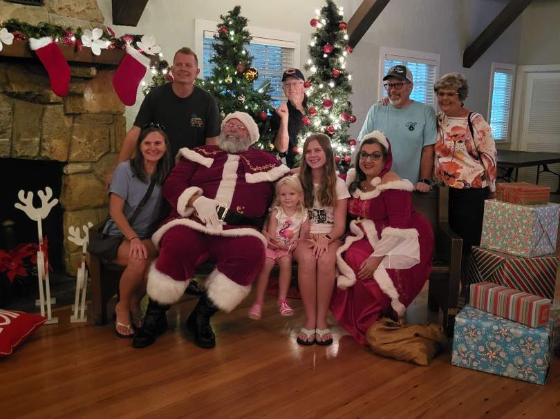 People at a Christmas party surrounding Santa Claus