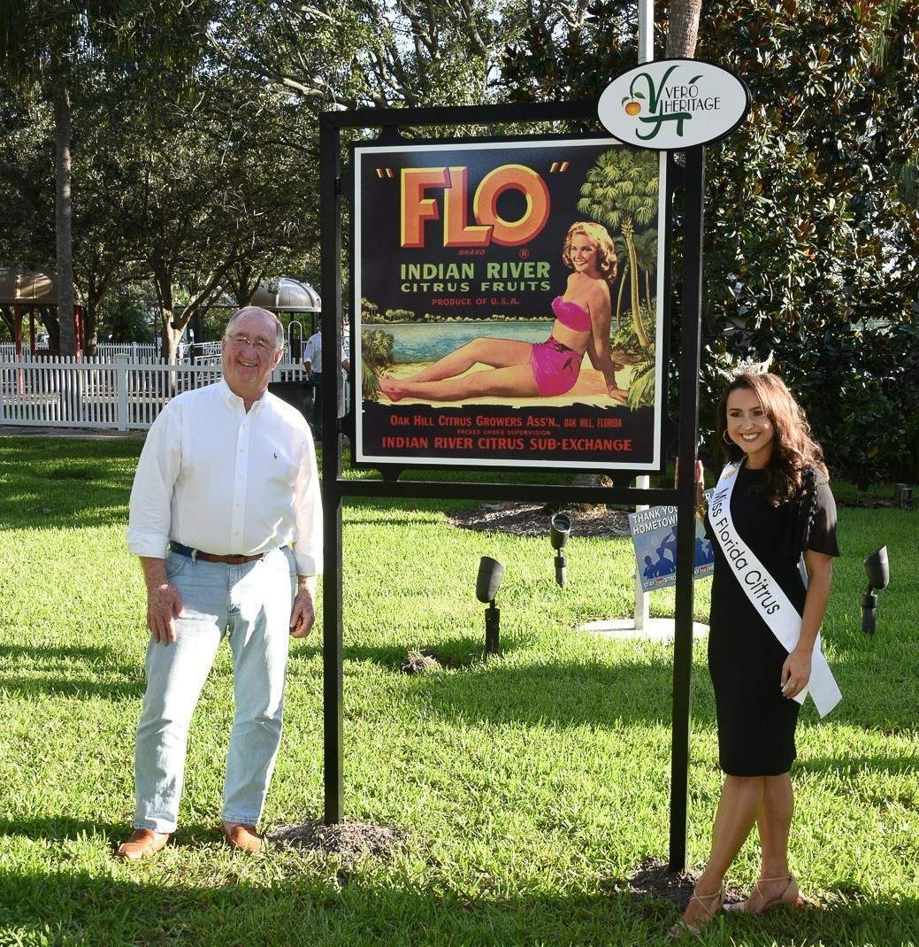 A man and women standing next to a sign that says FLO
