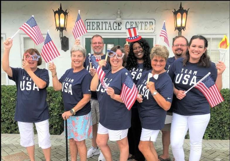 Group standing in front of the building holding American flags