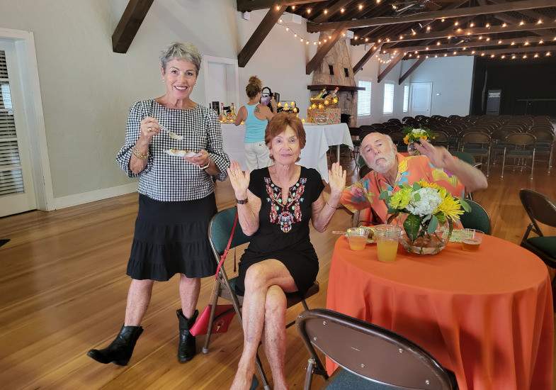 Two women and one man sitting at a table with happy smiles.